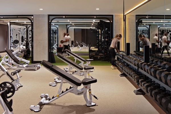 Verve Ann Arbor modern gym with benches, dumbbells, weight racks, and people working out in front of large mirrors.