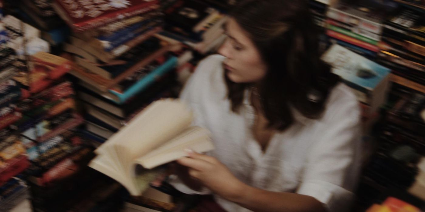 Young woman sitting on the floor in library amongst a pile of books