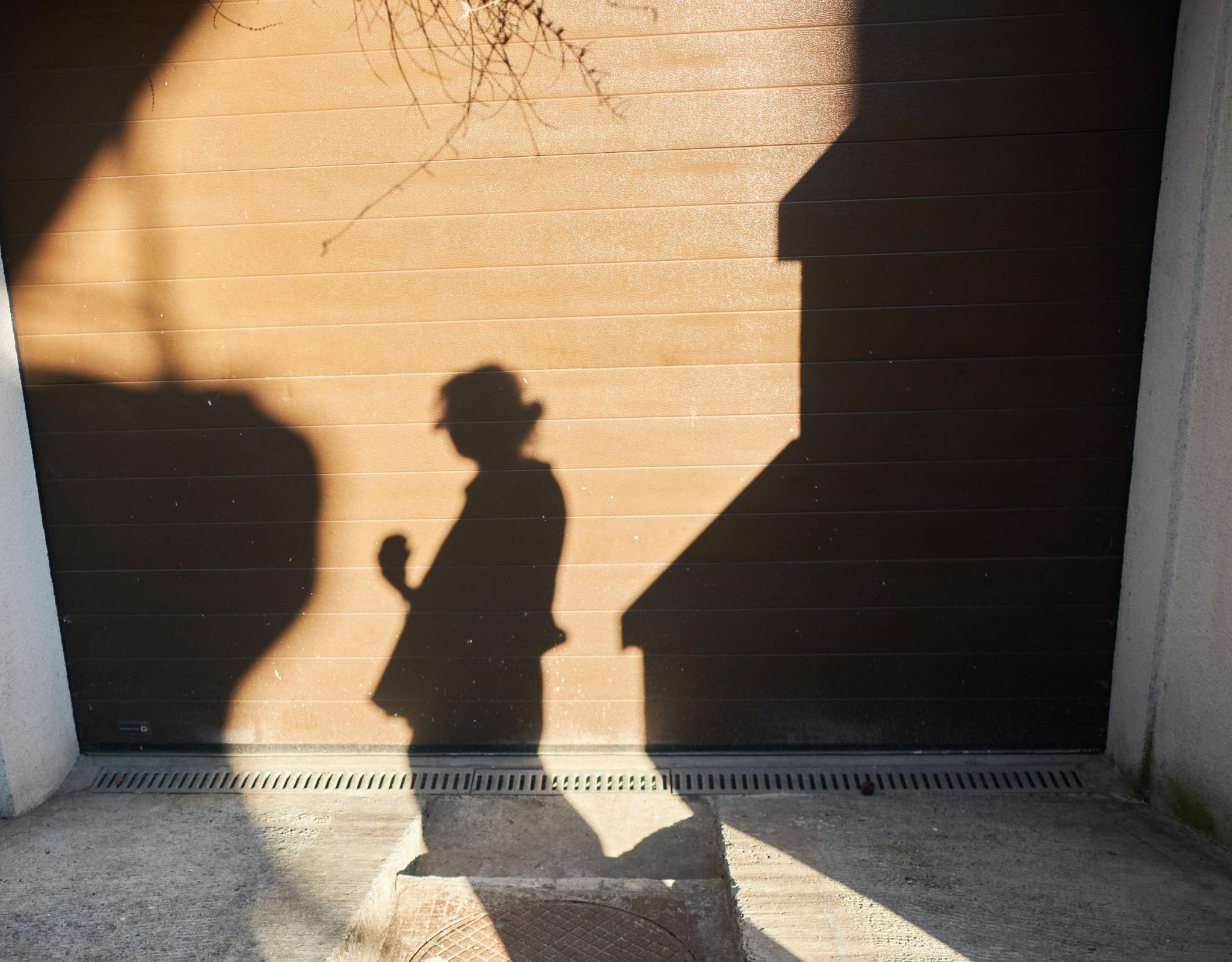 Shadow of person projected onto a city wall and sidewalk