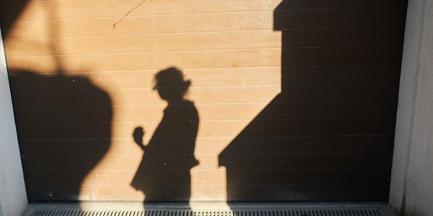 Shadow of person projected onto a city wall and sidewalk