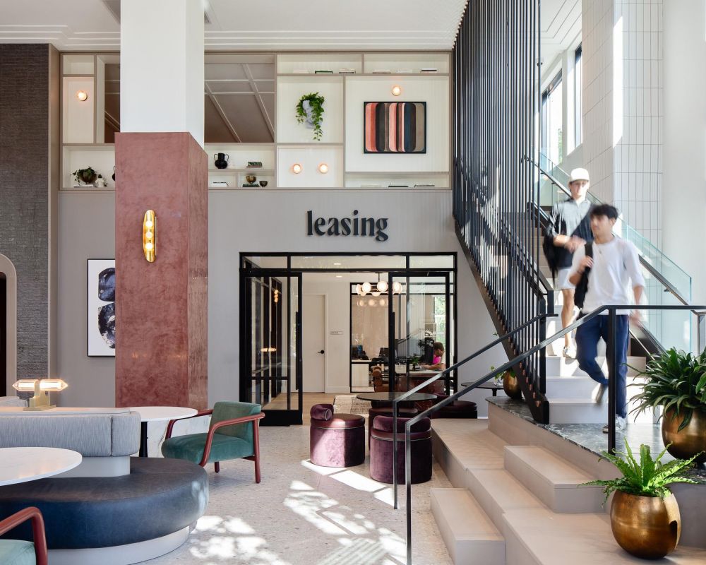 Verve Ann Arbor 现代化的租赁办公室大厅，摆放着时尚的家具，人们从楼梯上走下来，空间内摆放着植物。