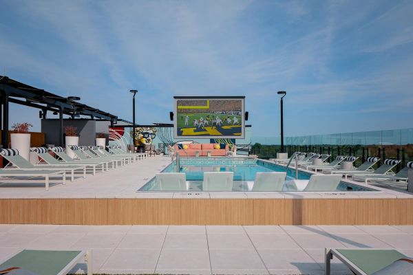 Verve Ann Arbor rooftop pool area with lounge chairs and a large outdoor TV screen showing a football game.